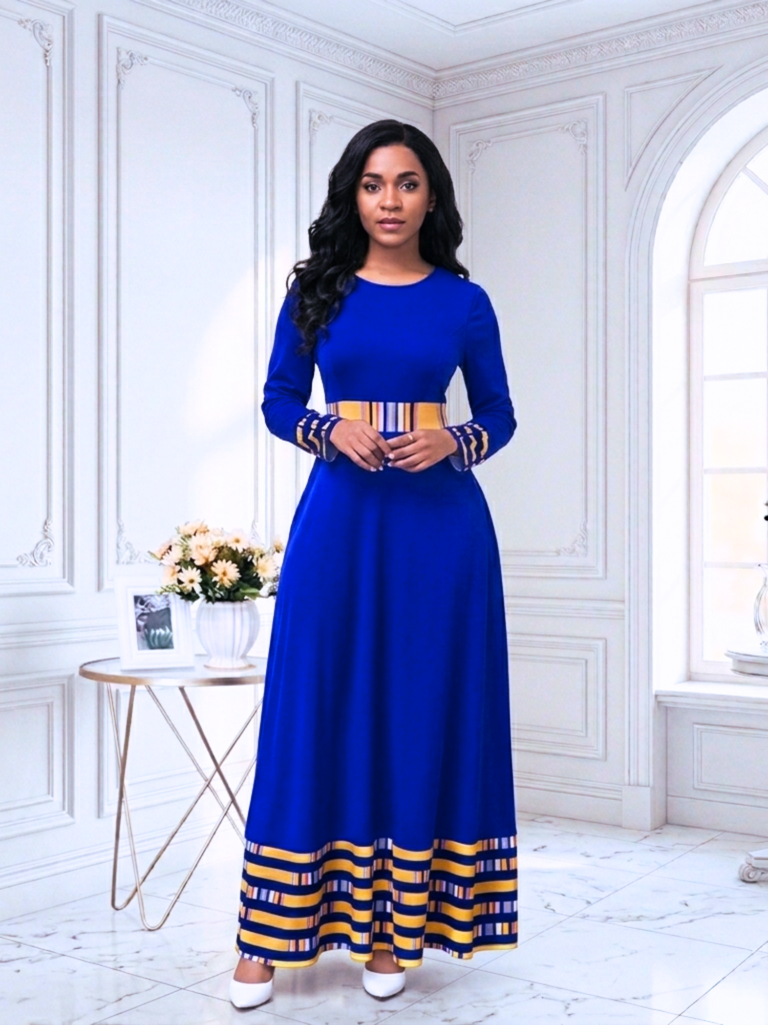 Woman wearing a blue dress with yellow accents in a white room.