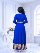 Woman wearing a blue dress with yellow accents in a white room.