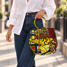 Syda African print Ankara handbag in yellow, burgundy and navy with circular handle and gold-tone chain.