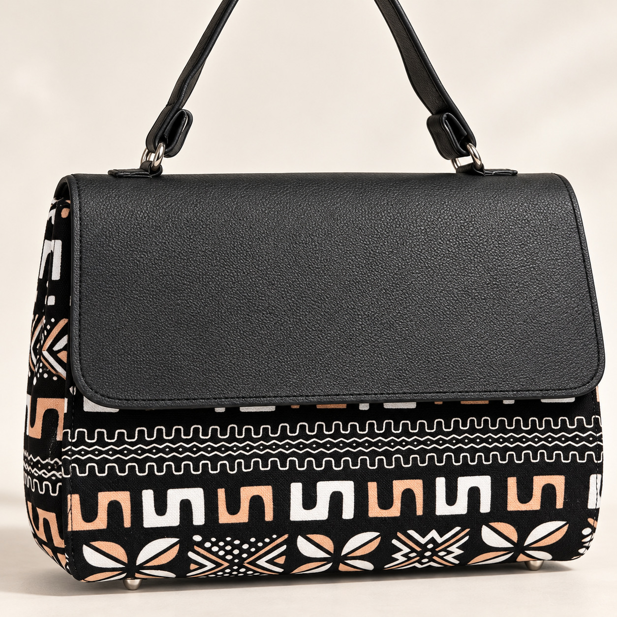 Close-up of Hananie handbag showing black textured flap, shoulder strap and African-inspired geometric fabric print.
