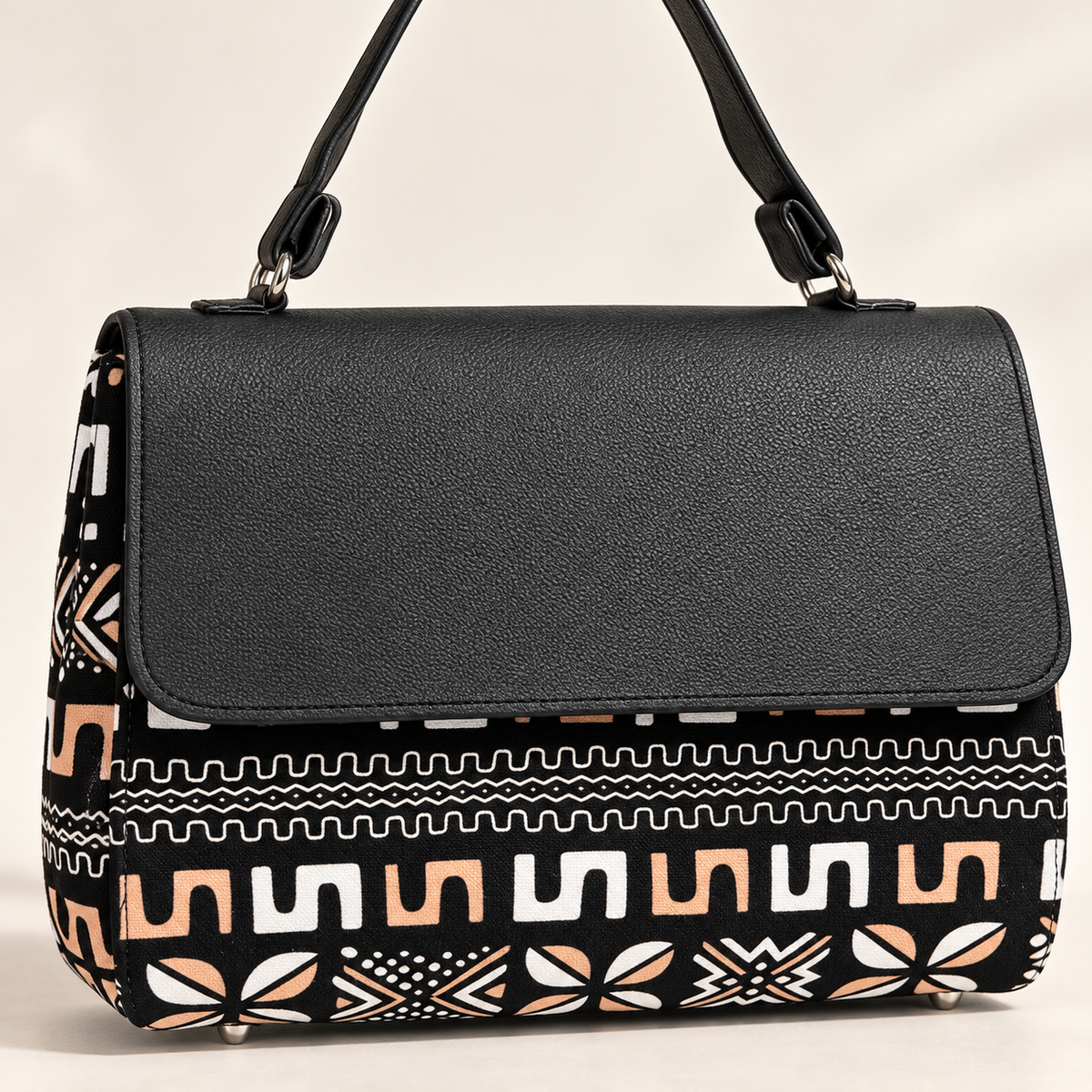 Close-up of Hananie handbag showing black textured flap, shoulder strap and African-inspired geometric fabric print.