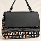 Close-up of Hananie handbag showing black textured flap, shoulder strap and African-inspired geometric fabric print.