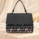 Model wearing the Hananie black mudcloth print shoulder bag with a cream blazer and elegant outfit.
